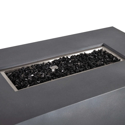 Angled close-up of the Flame Havens Refuge Series 56 x 30 x 24-inch rectangular propane gas fire pit in gray GFRC concrete. The recessed stainless steel burner pan is filled with reflective black fire glass, with the perforated ignition cover visible near the center against a clean white background.