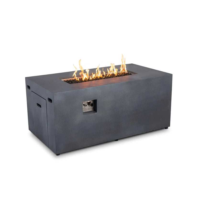 Angled view of the Flame Havens Refuge Series 56 x 30 x 24-inch rectangular propane gas fire pit in gray GFRC concrete. Yellow-orange flames burn across tempered black fire glass inside the recessed burner pan, while the front ignition and flame controls, hidden tank drawer and side ventilation openings remain visible against a white background.
