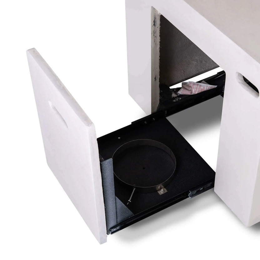 Open hidden propane tank drawer on the white Flame Havens Refuge Series 56 x 30 x 24-inch rectangular GFRC concrete fire pit, showing the empty black sliding platform, circular tank holder, securing hardware, side ventilation openings, and integrated concrete drawer front.