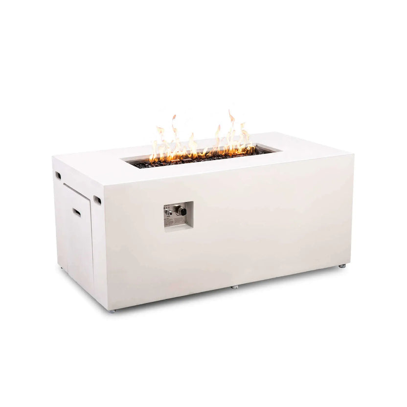 Angled view of the Flame Havens Refuge Series 56 x 30 x 24-inch rectangular propane gas fire pit in white GFRC concrete, shown burning over tempered black fire glass with a recessed ignition button and flame control knob, hidden tank drawer, side vents, and adjustable feet.