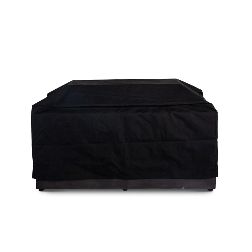 Straight front view of the black canvas fabric cover fitted over the Flame Havens Refuge Series 56 x 30 x 24-inch rectangular GFRC propane fire pit with its glass wind guard underneath. The raised cover accommodates the wind guard while extending across the top and sides of the fire pit.