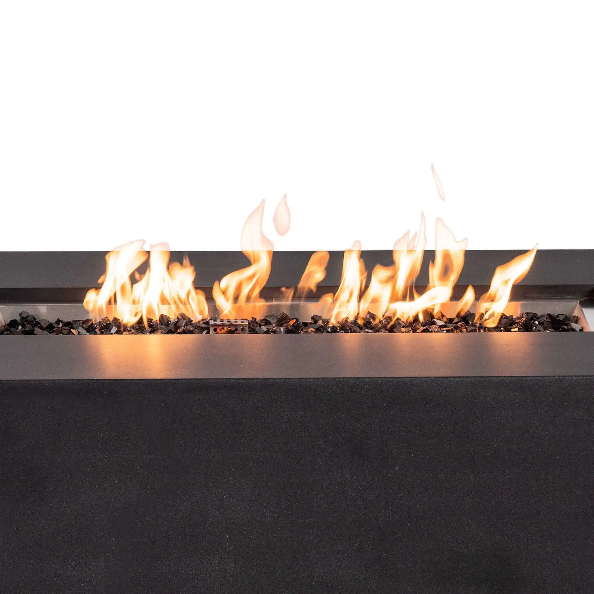Close-up of bright flames burning across tempered black fire glass in the Flame Havens Refuge Series 56 x 30 x 24-inch rectangular GFRC propane fire pit. The stainless steel burner pan, protective ignition cage, reflective black glass, and textured black concrete surround are clearly visible.