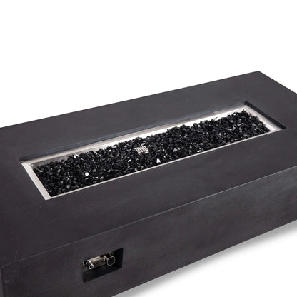 Angled close view of the Flame Havens Refuge Series 68 x 30 x 15-inch rectangular natural gas fire pit in black GFRC concrete. The recessed stainless steel burner pan is filled with reflective black fire glass, while the built-in ignition and flame control panel is visible on the front.
