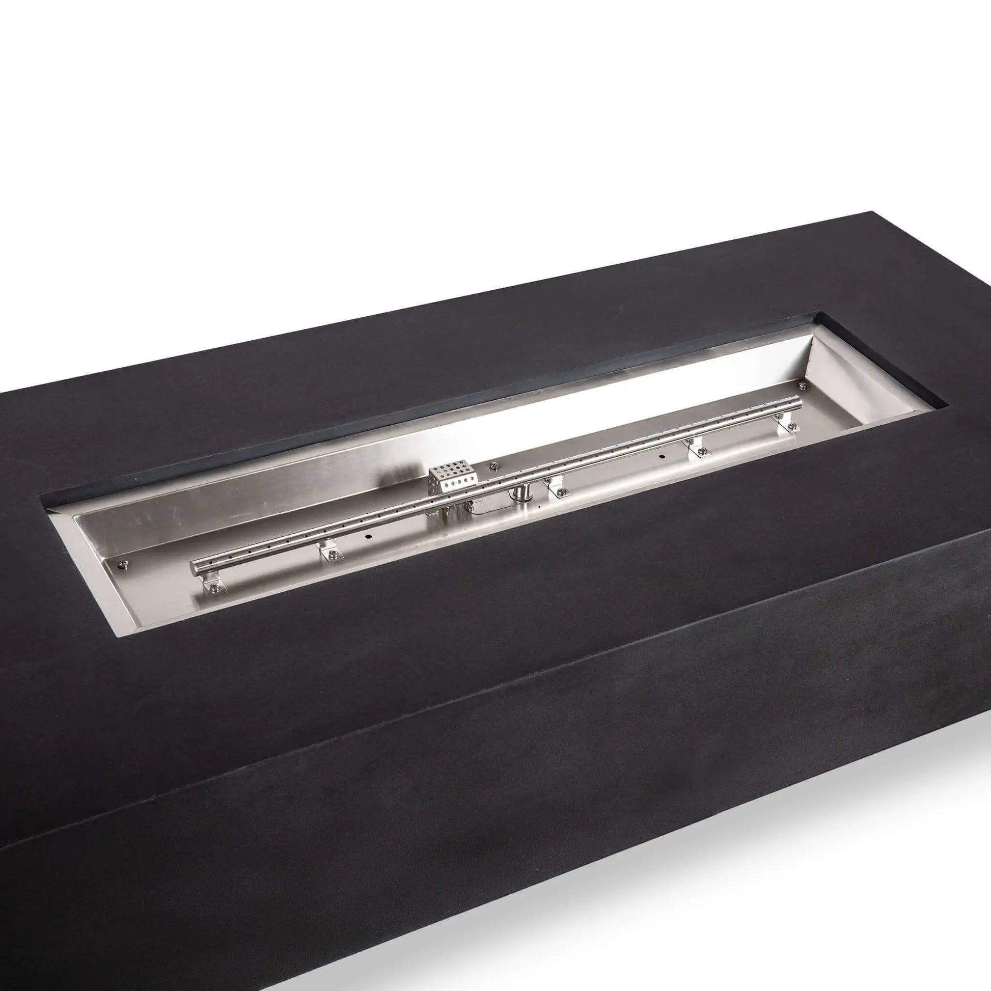 Angled close-up of the Flame Havens Refuge Series black GFRC concrete fire pit with its fire media removed. The open rectangular pan clearly displays the stainless steel natural gas burner assembly, mounting brackets, burner ports, and CSA ignition housing inside the 68 x 30 x 15-inch unit.