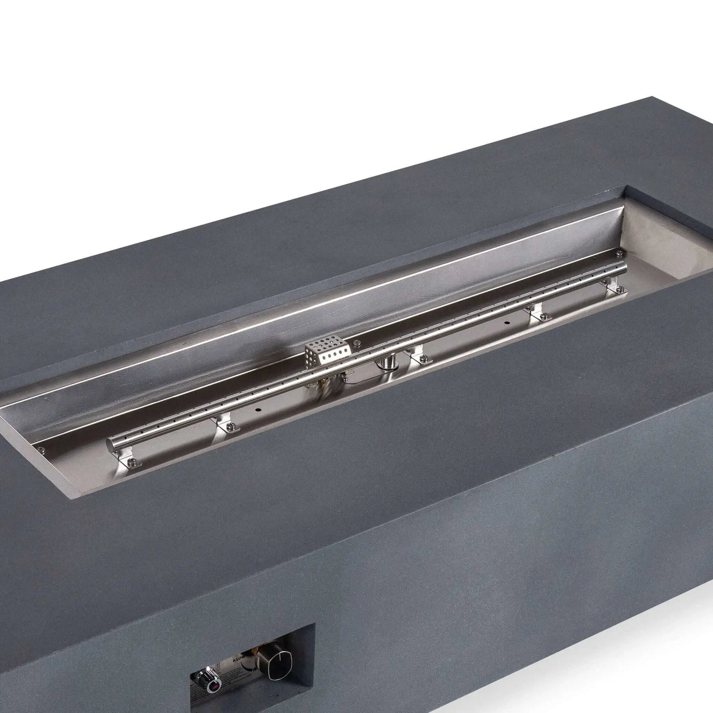 Close angled view of the Flame Havens Refuge Series 68 x 30 x 15-inch natural gray GFRC fire pit with the fire media removed. The image highlights the stainless steel burner pan, linear natural gas burner, ignition cage, mounting hardware, and recessed front control panel.