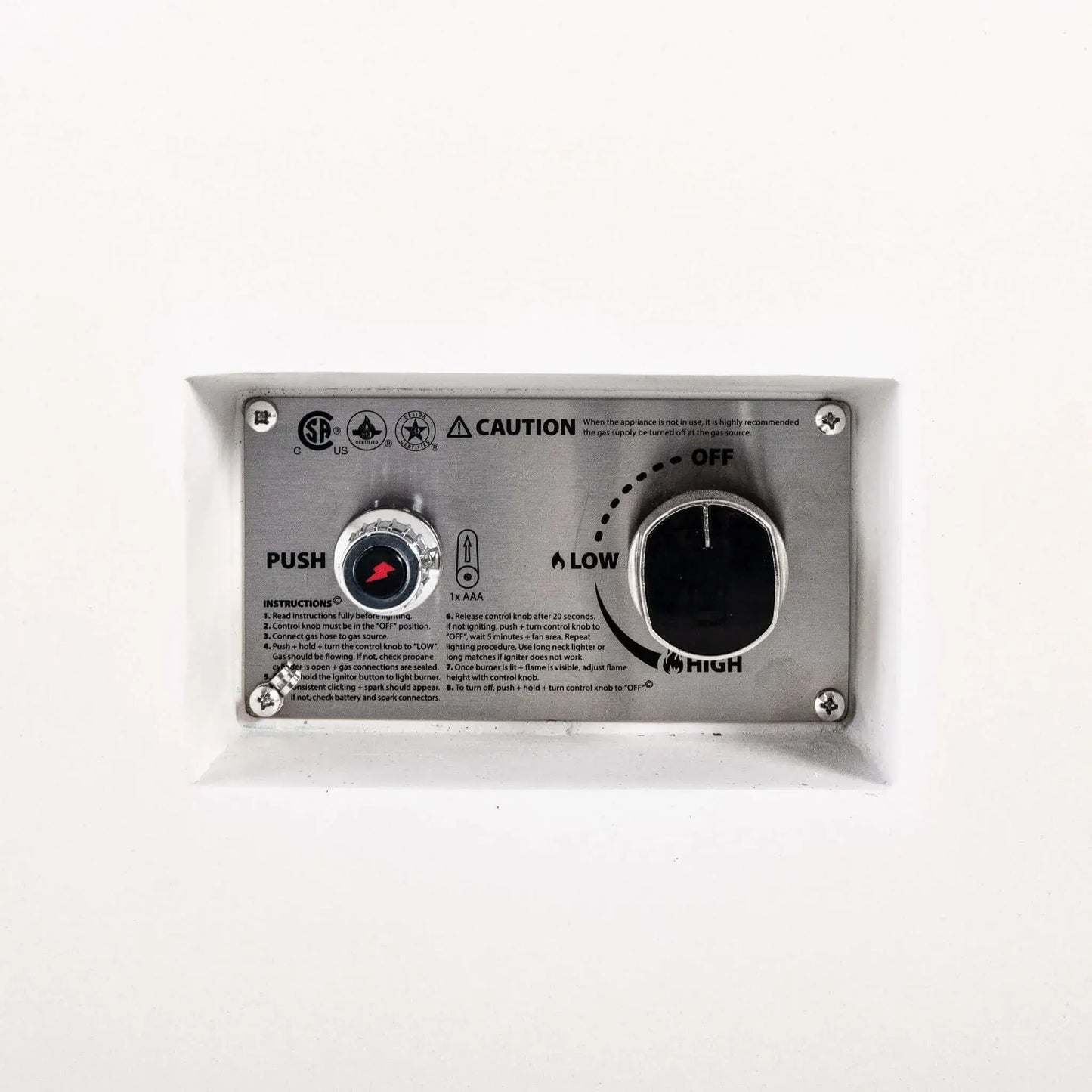 Close-up of the recessed CSA ignition controls on a Flame Havens Refuge Series 68 x 30 x 15-inch white GFRC natural gas fire pit. The stainless steel panel includes a battery-powered push-button igniter, large gas control knob with OFF, LOW and HIGH settings, lighting instructions and safety markings.