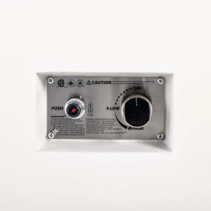Close-up of the recessed CSA ignition controls on a Flame Havens Refuge Series 68 x 30 x 15-inch white GFRC natural gas fire pit. The stainless steel panel includes a battery-powered push-button igniter, large gas control knob with OFF, LOW and HIGH settings, lighting instructions and safety markings.