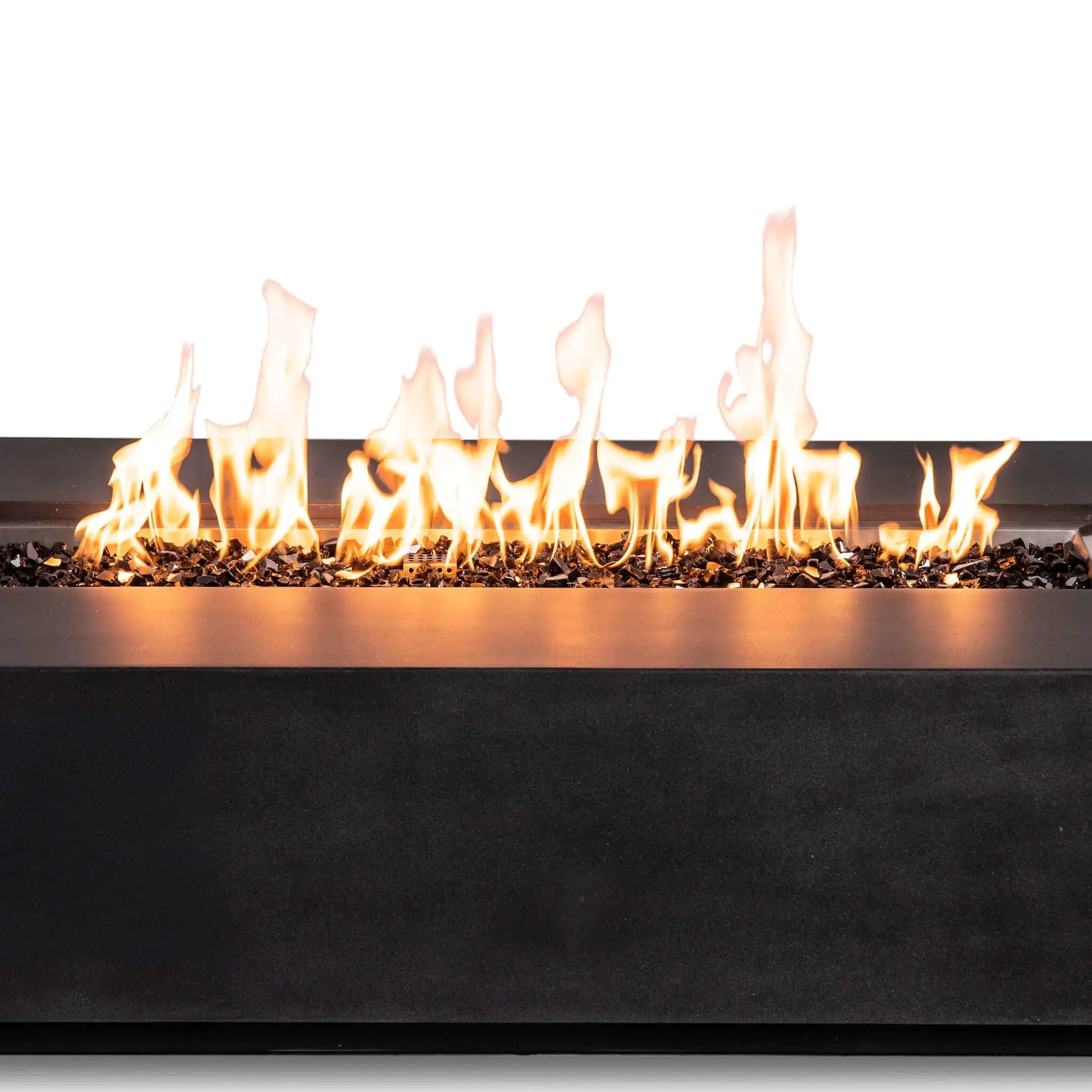 Close-up of active natural gas flames stretching across reflective tempered black fire glass in the Flame Havens Refuge Series 68 x 30 x 15-inch rectangular fire pit. The image highlights the varied flame heights, stainless steel burner-pan edge, dark GFRC concrete finish, and concealed-control design.