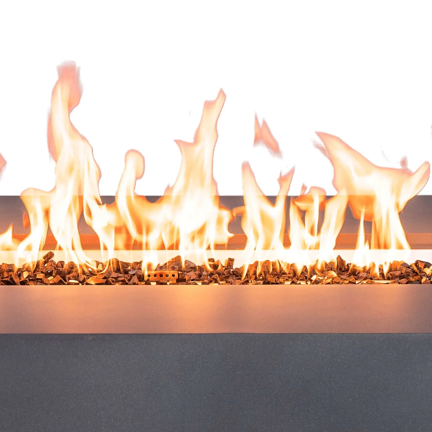 Close-up of tall natural gas flames burning across tempered black fire glass in the Flame Havens Refuge Series 68 x 30 x 15-inch rectangular fire pit. The bright linear flame reflects across the dark glass media and stainless steel burner pan, with the natural gray GFRC concrete edge visible below.