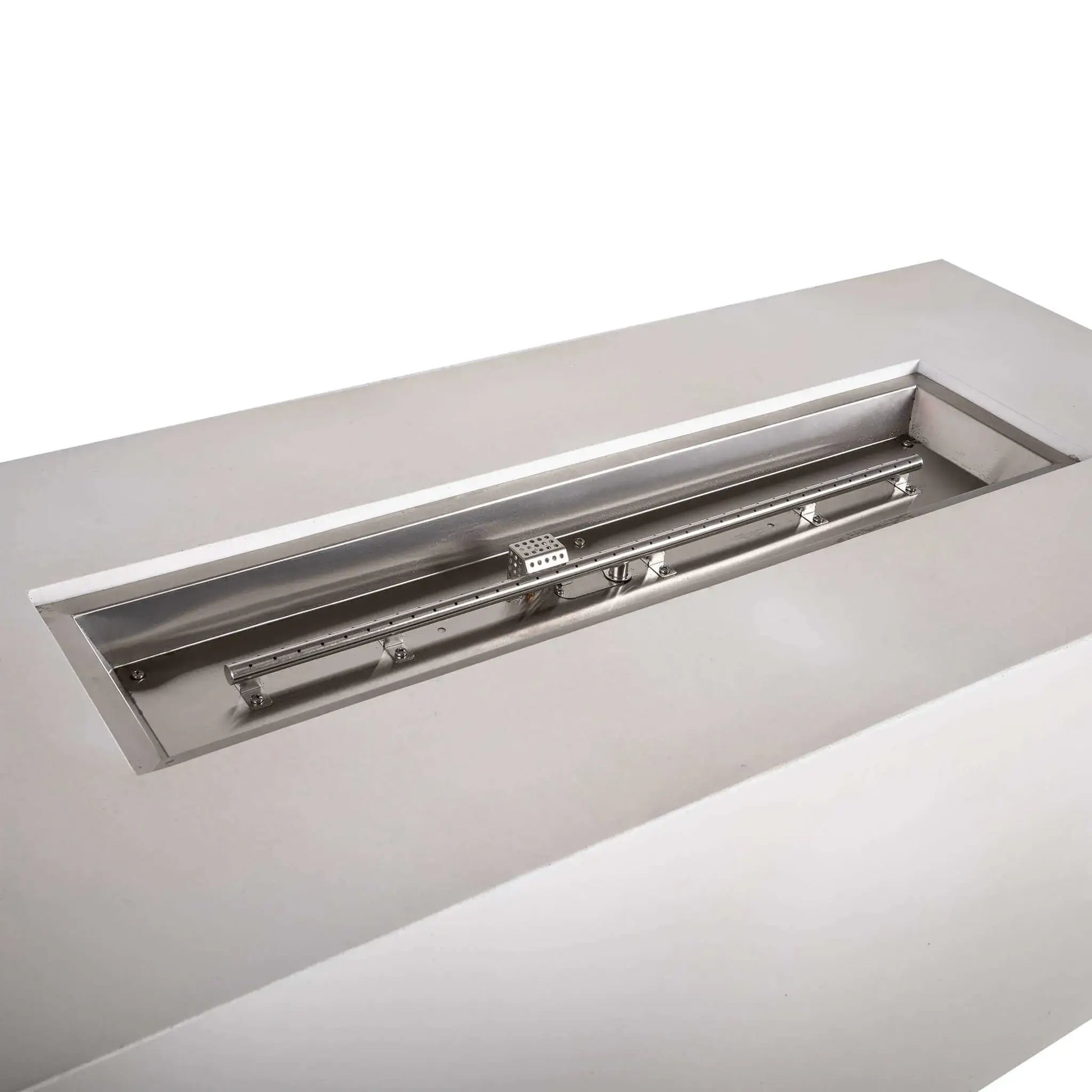 Close-up of the Flame Havens Refuge Series stainless steel burner assembly inside a white 68 x 30 x 24-inch rectangular GFRC propane fire pit. The clean burner pan, long linear burner tube, mounting brackets, gas connection, and perforated CSA ignition cage are shown before fire glass is added.