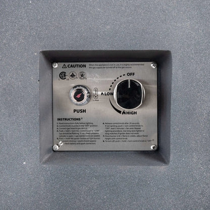 Close-up of the recessed CSA ignition controls on the Flame Havens Refuge Series gray propane gas fire pit, showing the push-button spark igniter, adjustable control knob with OFF, LOW, and HIGH settings, operating instructions, and safety markings on a stainless steel panel.