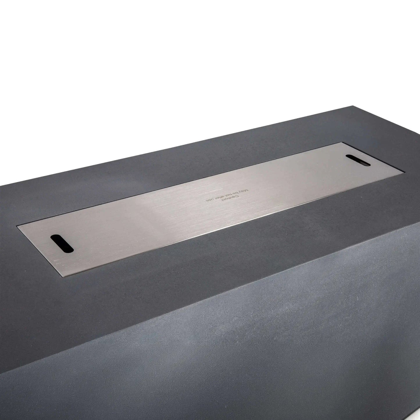 Close-up of the Flame Havens Refuge Series 68 x 30 x 24-inch rectangular gray propane gas fire pit fitted with a flush stainless steel burner cover, featuring two integrated hand openings and a centered caution marking over the concealed fire glass and burner pan.