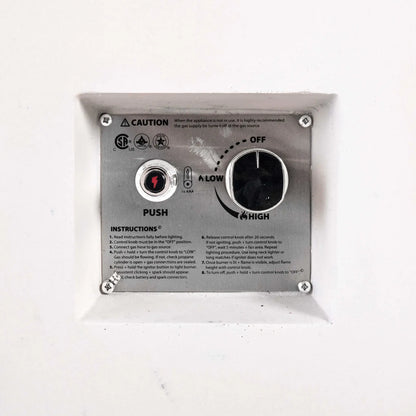 Close-up of the recessed CSA ignition controls on the Flame Havens Refuge Series 68 x 30 x 24-inch white rectangular propane fire pit. The stainless steel panel includes a push-button battery ignitor, large flame control knob with off, low, and high settings, safety certifications, caution notice, and lighting instructions.
