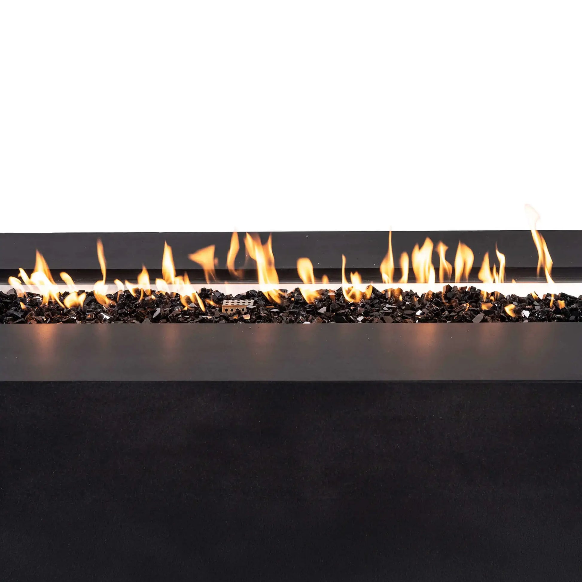 Close-up of bright orange flames burning across reflective tempered black fire glass in the Flame Havens Refuge Series 68 x 30 x 24-inch rectangular black GFRC concrete propane fire pit. The linear flame pattern, stainless steel burner pan, and protective ignition cage are visible against a clean white background.
