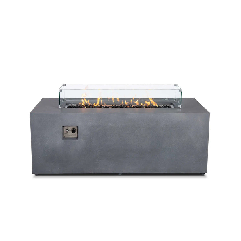 Straight front view of the Flame Havens Refuge Series 68 x 30 x 24-inch rectangular gray propane fire pit with flames burning over tempered black fire glass. A clear glass wind guard with stainless steel corner brackets surrounds the linear burner.