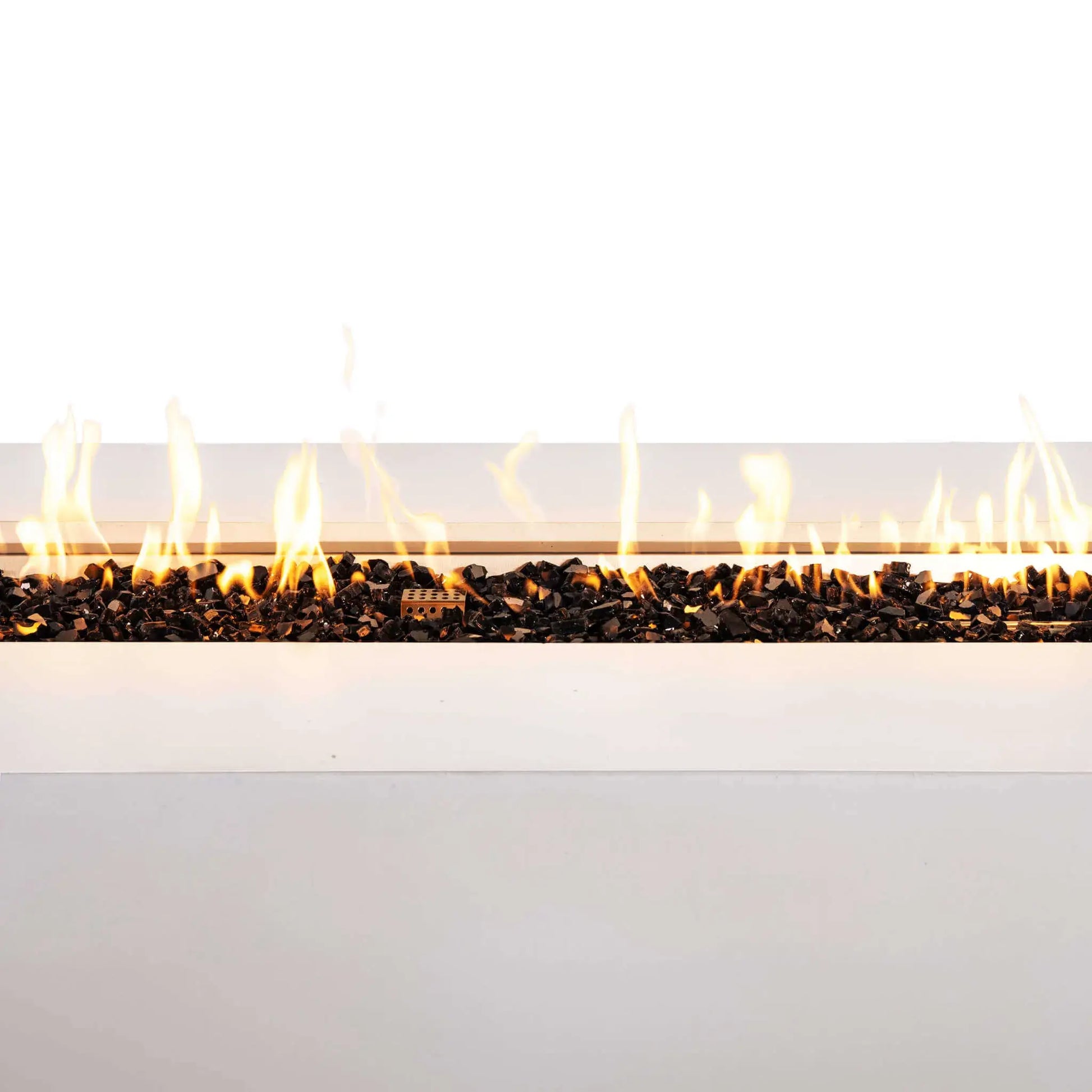 Close-up of the Flame Havens Refuge Series 68 x 30 x 24-inch rectangular propane gas fire pit in white GFRC concrete. A continuous row of bright flames rises above reflective tempered black fire glass, with the protective stainless steel ignition cage visible near the center of the burner.