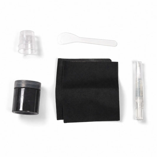 Contents of the Flame Havens Refuge Series Black concrete surface care kit arranged on a white background. The color-matched repair set includes a jar of black material, two black application pads, small clear mixing cups, a plastic mixing spoon, and a clear pen-style applicator.