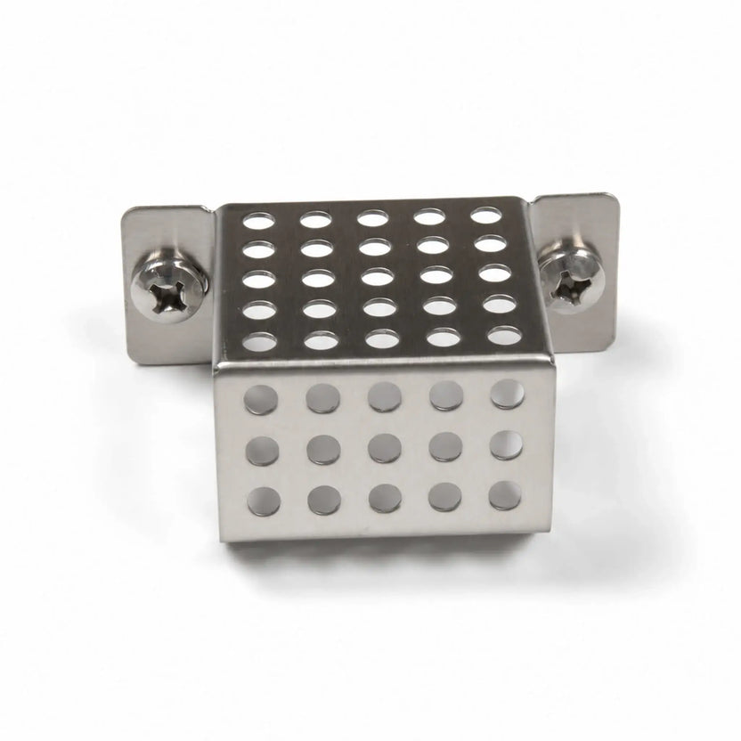 Front view of the Flame Havens Refuge Series ignition shield on a white background. The compact stainless steel fire pit part features a perforated, box-shaped cover with rows of round ventilation holes, folded mounting tabs, and two Phillips-head screws securing the shield assembly.