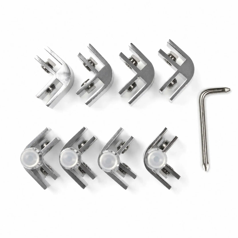 Top view of the Flame Havens Refuge Series rectangle and square tempered glass wind guard hardware kit. Arranged on a white background, the set includes eight polished metal corner clamps with cushioned glass channels, adjustment screws, four clear support feet, and an L-shaped driver tool for assembly.