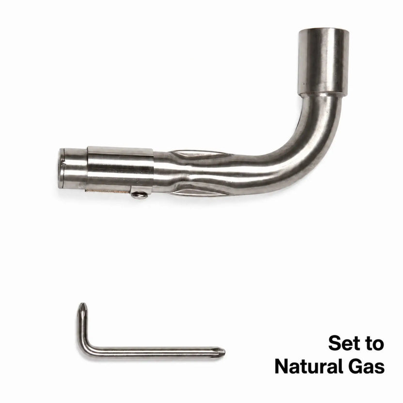 Flame Havens Refuge Series propane and natural gas Venturi pipe shown in the natural gas position. The stainless steel L-shaped pipe has a curved burner connection and an adjustable sleeve covering the air intake screen. An L-shaped adjustment tool appears below, with bold text reading “Set to Natural Gas” in the lower-right corner.