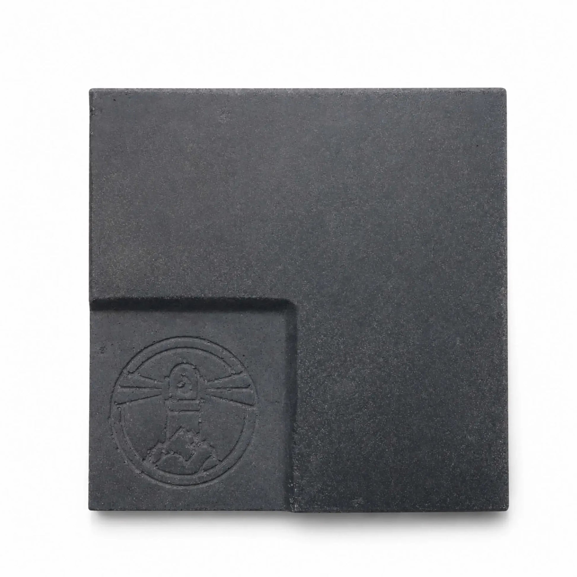 Flame Havens Refuge and Serenity Series GFRC glass fiber reinforced concrete sample in Graphite Black. The square finish swatch has a deep charcoal-black color, fine concrete texture, subtle tonal variation, softly rounded edges, and a recessed lower-left panel featuring an embossed Flame Havens emblem.