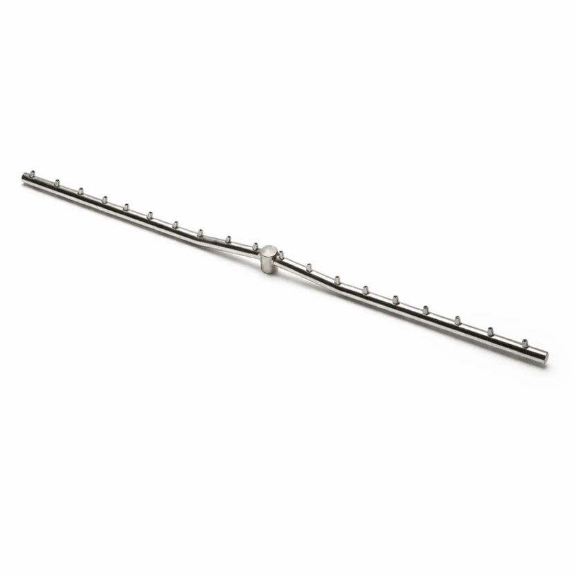 A stainless steel Torpedo T linear burner displayed on a clean white background, showing the T-shaped gas line with evenly spaced burner ports along both sides. The minimalist product shot highlights the precision design and construction of the fire pit burner component.