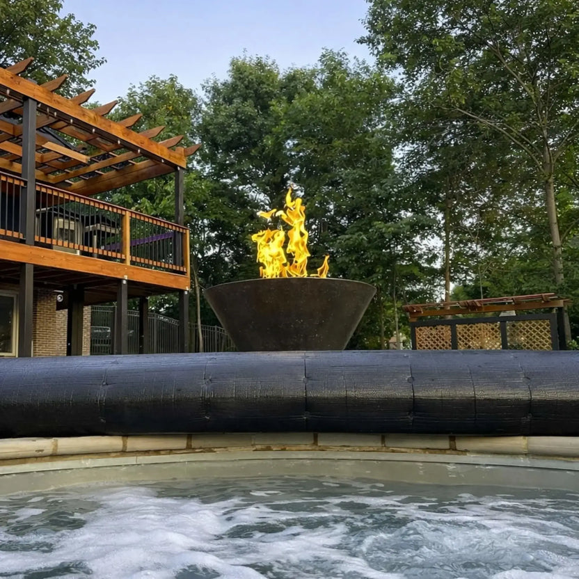 Modern backyard scene with HPC Copper Round Fire Bowl Mesa placed near a spa, showcasing a tall flame display, wood pergola structure, and landscaped surroundings, creating a luxury outdoor living space with fire feature focal point.