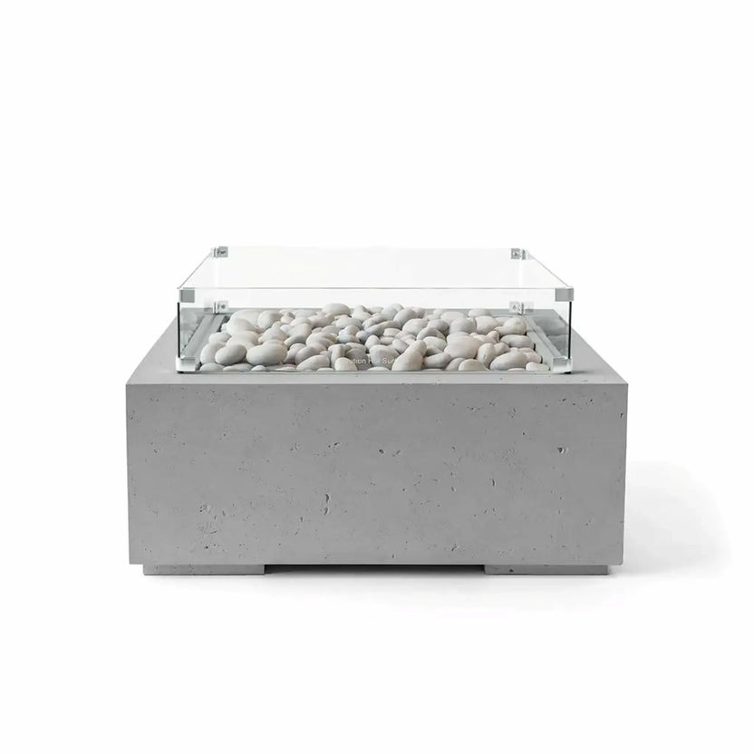 Front-facing image of the HPC Fire Hearth Products Controls Dekko GFRC Concrete Alea 32 x 32 Fire Pit in Charcoal finish with ivory fire stones and a clear tempered glass wind guard. The dark gray GFRC concrete construction contrasts beautifully with the light stone media, emphasizing the modern square fire pit design for outdoor living and entertainment areas.