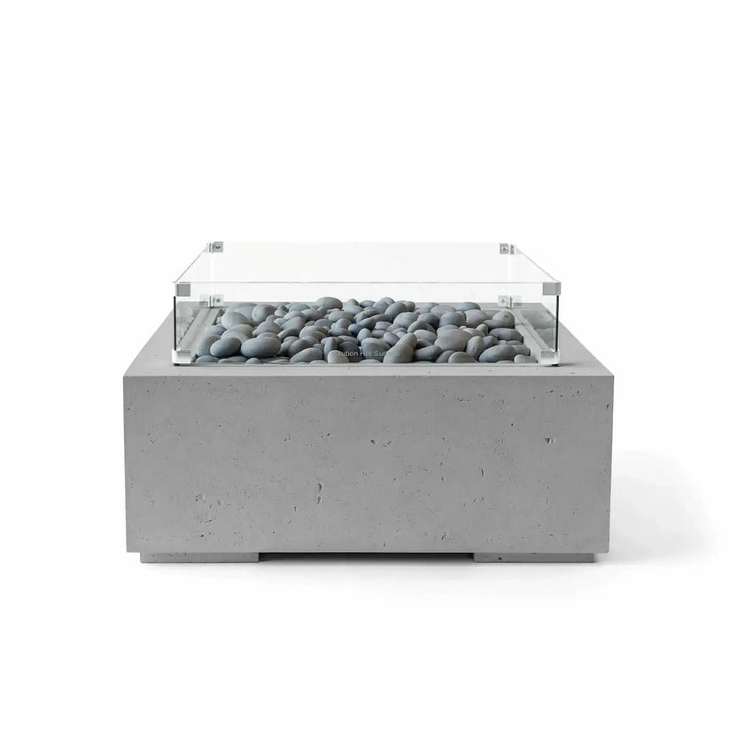 Studio product image of the HPC Fire Hearth Products Controls Dekko GFRC Concrete Alea 32 x 32 Fire Pit in Charcoal finish with gray slate stone media and a tempered glass wind guard. The square outdoor fire table combines modern GFRC concrete construction, neutral tones, and decorative fire stones for a refined contemporary patio centerpiece.