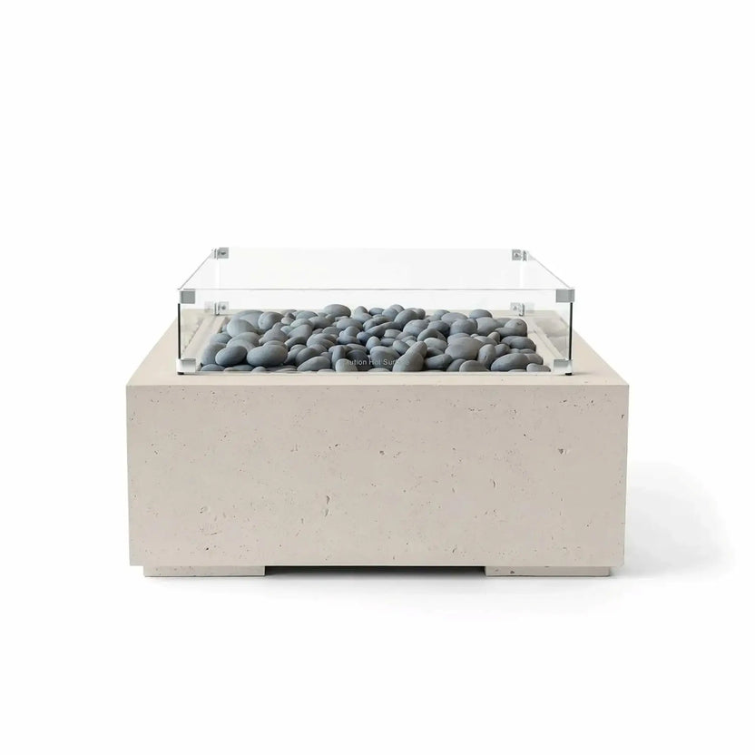 Front-facing product photo of the HPC Fire Hearth Products Controls Dekko GFRC Concrete Alea 32 x 32 Fire Pit in Clay finish featuring smooth gray slate stones beneath a clear tempered glass wind guard. The square fire pit showcases durable GFRC concrete construction, modern styling, and decorative fire media designed for upscale outdoor living environments.