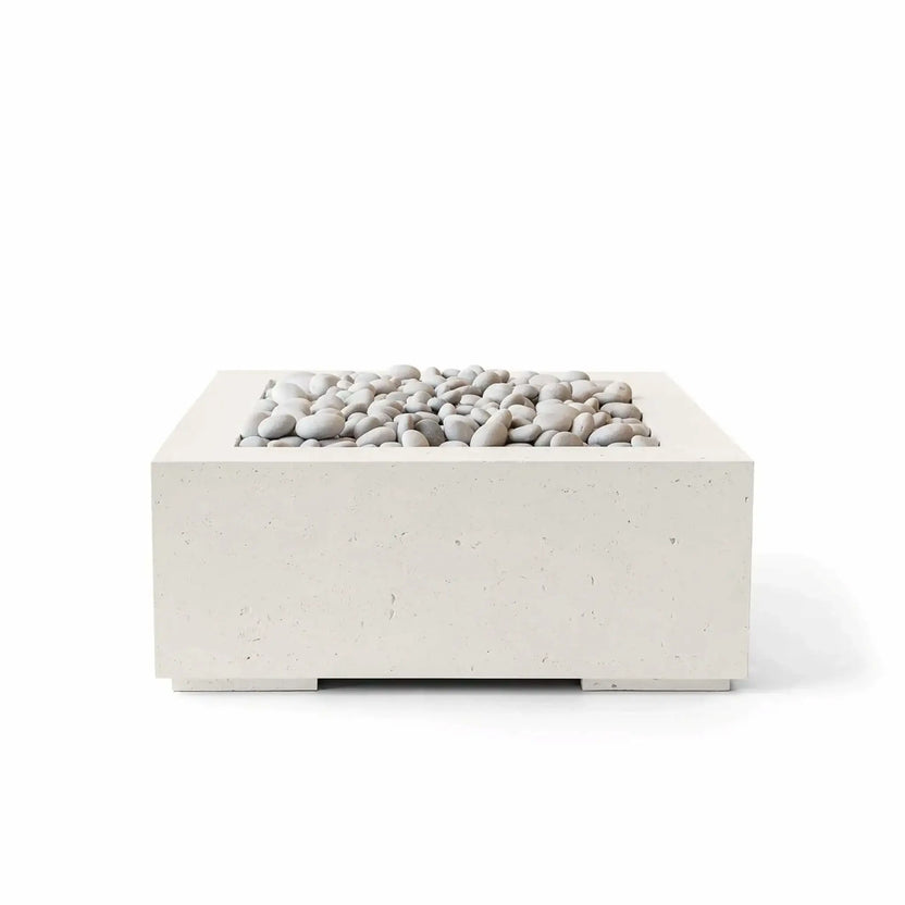 HPC Fire Hearth Products Controls Dekko GFRC Concrete Alea 32 x 32 Fire Pit in Limestone finish with ivory decorative stones. This modern square outdoor fire pit features durable glass fiber reinforced concrete construction, a clean minimalist profile, and a recessed burner area filled with smooth white stones. The warm limestone color makes the Alea fire pit a versatile addition to contemporary patios, courtyards, and outdoor living spaces.