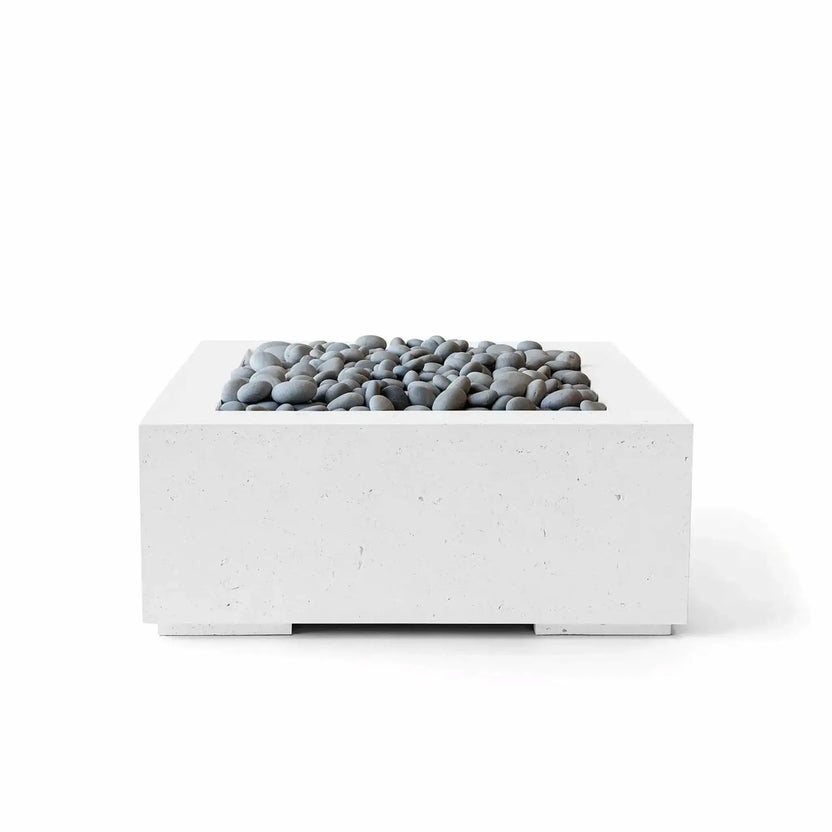 HPC Fire Hearth Products Controls Dekko GFRC Concrete Alea 32 x 32 Fire Pit in Natural finish with polished slate stone media. The square fire pit features a minimalist low-profile design, textured GFRC concrete body, and smooth gray decorative stones surrounding the recessed burner compartment. Designed for contemporary outdoor living spaces, the Alea fire pit provides a sophisticated focal point for patios, courtyards, and modern landscape designs.