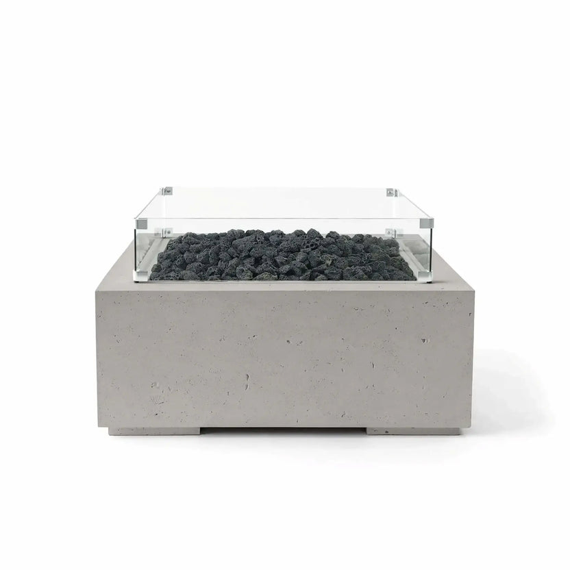 Front view of the HPC Fire Hearth Products Controls Dekko GFRC Concrete Alea 32 x 32 Fire Pit in Sandstone finish with black lava rock media and a tempered glass wind guard. The square GFRC concrete fire feature combines warm neutral tones, contemporary design, and rugged lava rock accents, shown in a professional white-background product photograph.