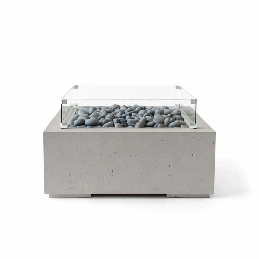 HPC Fire Hearth Products Controls Dekko GFRC Concrete Alea 32 x 32 Fire Pit in Sandstone finish with smooth gray slate stone fire media and a tempered glass wind guard. This square outdoor fire pit features a textured GFRC concrete construction, warm sandstone appearance, and modern low-profile silhouette designed for contemporary outdoor entertaining spaces.