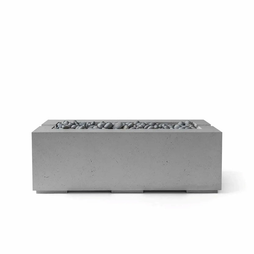 HPC Fire & Hearth Products Controls Dekko GFRC Concrete Avera 48 x 26 Fire Pit in Charcoal finish with smooth Slate Stone media. The rectangular fire pit showcases a clean-lined GFRC concrete exterior and a recessed linear burner channel filled with gray decorative stones. This sophisticated outdoor fire feature blends modern styling with durable construction, creating an attractive focal point for patios, terraces, and outdoor lounge areas.