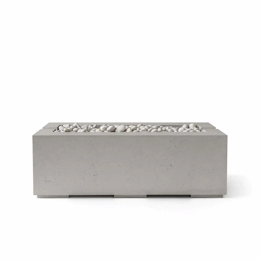 HPC Fire & Hearth Products Controls Dekko GFRC Concrete Avera 48 x 26 Fire Pit in Sandstone finish featuring Ivory Stone media. The rectangular GFRC concrete fire pit showcases a warm beige sandstone-colored exterior paired with smooth white decorative stones across the linear burner tray. Captured as a clean studio product image on a white background, the Avera fire pit blends contemporary styling with durable construction, making it an attractive focal point for outdoor entertaining and backyard retreats.