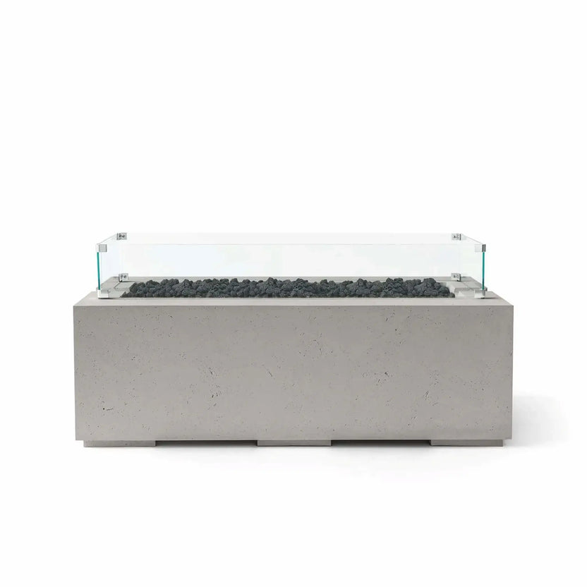 HPC Fire & Hearth Products Dekko GFRC Concrete Avera 48 x 26 Fire Pit Sandstone Lava Rock Tempered Glass Wind Guard featuring dark lava rock media set within a stainless burner tray. The sandstone-colored GFRC concrete fire table is paired with a transparent tempered glass wind guard that enhances visibility and wind resistance while maintaining the fire pit’s modern, low-profile outdoor design.