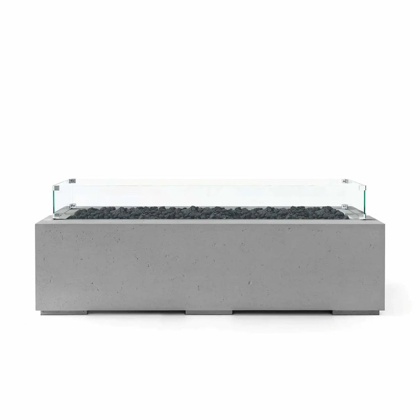HPC Fire Hearth Products Controls Dekko GFRC Concrete Avera 60 x 26 Fire Pit featuring a Charcoal finish, black lava rock media, and a clear tempered glass wind guard. The sleek rectangular fire pit combines textured GFRC concrete construction with a modern linear burner layout, creating a sophisticated outdoor centerpiece suitable for patios, terraces, and luxury backyard entertainment spaces.