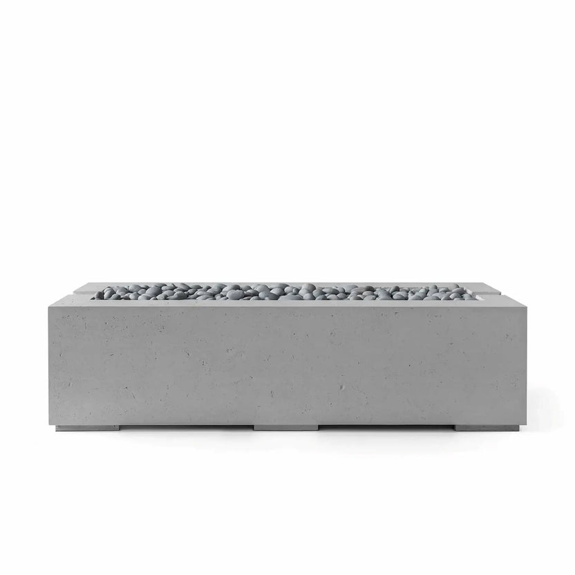 Dekko GFRC Concrete Avera 60 x 26 Fire Pit by HPC Fire Hearth Products Controls featuring a Charcoal finish and Slate Stone burner media. The elongated rectangular fire feature combines a textured concrete exterior with decorative gray stones, creating a sophisticated focal point for modern patios, outdoor lounges, and residential landscape designs.