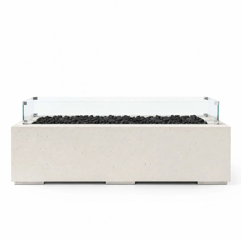 HPC Fire Hearth Products Controls Dekko GFRC Concrete Avera 60 x 26 Fire Pit in Limestone finish featuring natural black lava rock media and a clear tempered glass wind guard. This rectangular outdoor fire pit table showcases a durable GFRC concrete construction, clean contemporary lines, and a linear burner design, making it a stylish focal point for patios, outdoor lounges, and modern backyard living spaces.