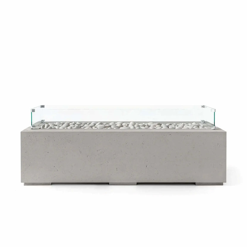 HPC Fire Hearth Products Controls Dekko GFRC Concrete Avera 60 x 26 Fire Pit in Sandstone finish featuring ivory fire stones and a clear tempered glass wind guard. The warm-toned rectangular fire pit offers durable GFRC concrete construction, a sleek linear burner configuration, and clean contemporary styling that complements outdoor seating areas, patios, and luxury landscape designs.