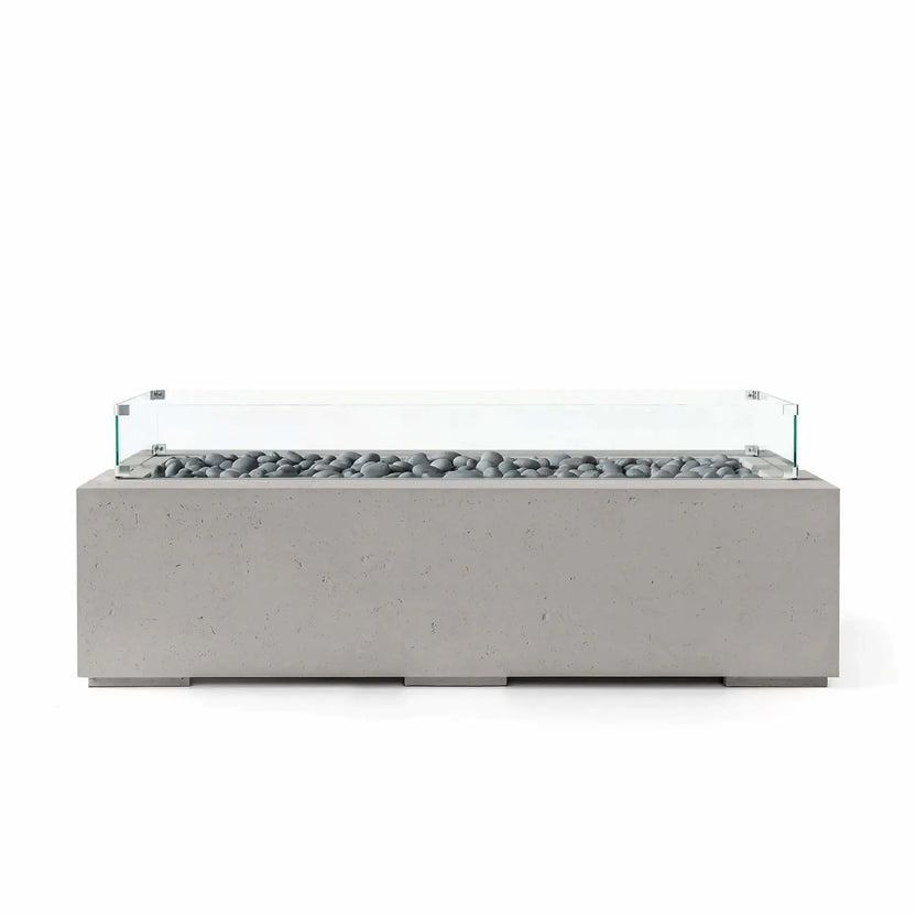 HPC Fire Hearth Products Controls Dekko GFRC Concrete Avera 60 x 26 Fire Pit in Sandstone finish with smooth slate stone media and a tempered glass wind guard. The rectangular fire pit table features a durable concrete-look GFRC body, low-profile modern design, and a linear burner enclosure that creates a refined centerpiece for contemporary outdoor living spaces.