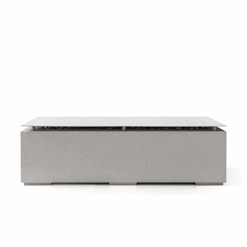 Front view of the HPC Fire Hearth Products Controls Dekko GFRC Concrete Avera 60 x 26 Fire Pit in Sandstone finish featuring a stainless steel table top lid. The rectangular outdoor fire pit displays a warm beige concrete texture, contemporary low-profile design, hidden burner section with decorative media underneath, and elegant modern styling suitable for patios and outdoor living areas.