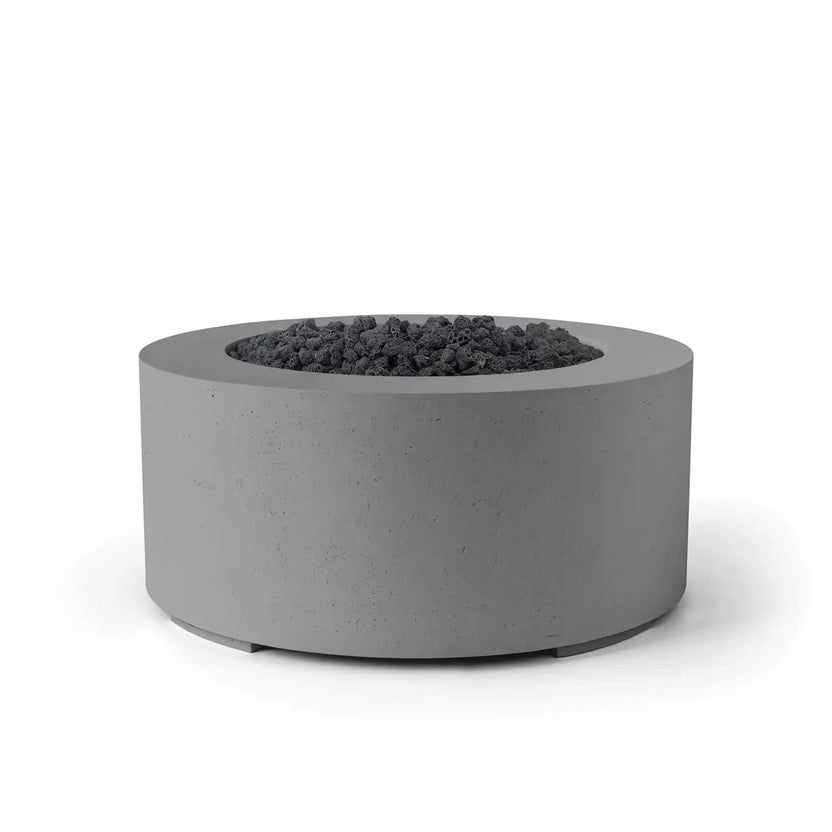 HPC Fire Hearth Products Controls Dekko GFRC Concrete Belmont Fire Pit finished in Charcoal and filled with black lava rock media. The round outdoor fire pit features durable GFRC concrete construction, a recessed burner compartment, and a clean cylindrical form. The dark-on-dark color combination creates a bold contemporary aesthetic suitable for modern patios, rooftop lounges, outdoor hospitality settings, and residential entertainment areas.
