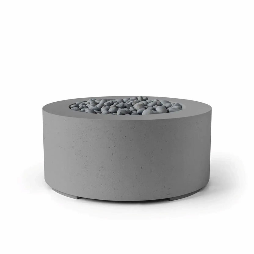 HPC Fire Hearth Products Controls Dekko GFRC Concrete Belmont Fire Pit in Charcoal finish featuring slate stone fire media. This modern round fire pit showcases a textured charcoal GFRC concrete body, wide top rim, and recessed burner opening filled with smooth gray stones. The sleek architectural design complements contemporary outdoor living spaces while providing a durable and attractive focal point for gathering areas.