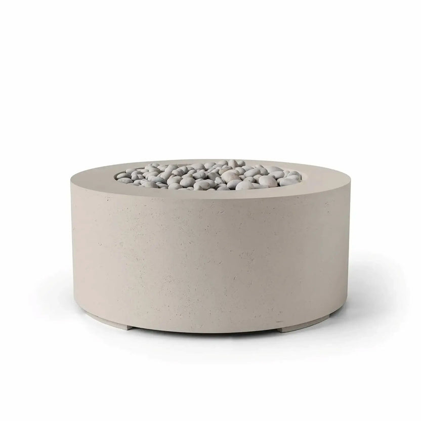 HPC Fire Hearth Products Controls Dekko GFRC Concrete Belmont Fire Pit in Clay finish with ivory stone media. This round 36-inch fire pit features a warm beige concrete tone, durable GFRC construction, and a recessed fire bowl filled with decorative smooth stones. The soft neutral color palette and contemporary cylindrical shape make it a stylish addition to patios, outdoor seating areas, courtyards, and landscape designs.