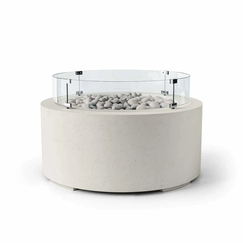 HPC Fire Hearth Products Controls Dekko GFRC Concrete Belmont Fire Pit in Limestone finish featuring Ivory Stone media and a Tempered Glass Wind Guard. The off-white GFRC concrete fire pit includes a round contemporary silhouette, decorative ivory fire stones, and a transparent glass windscreen that enhances safety and flame protection. Shown on a white background, this Belmont Fire Pit delivers a clean, upscale look for luxury outdoor living and entertainment areas.