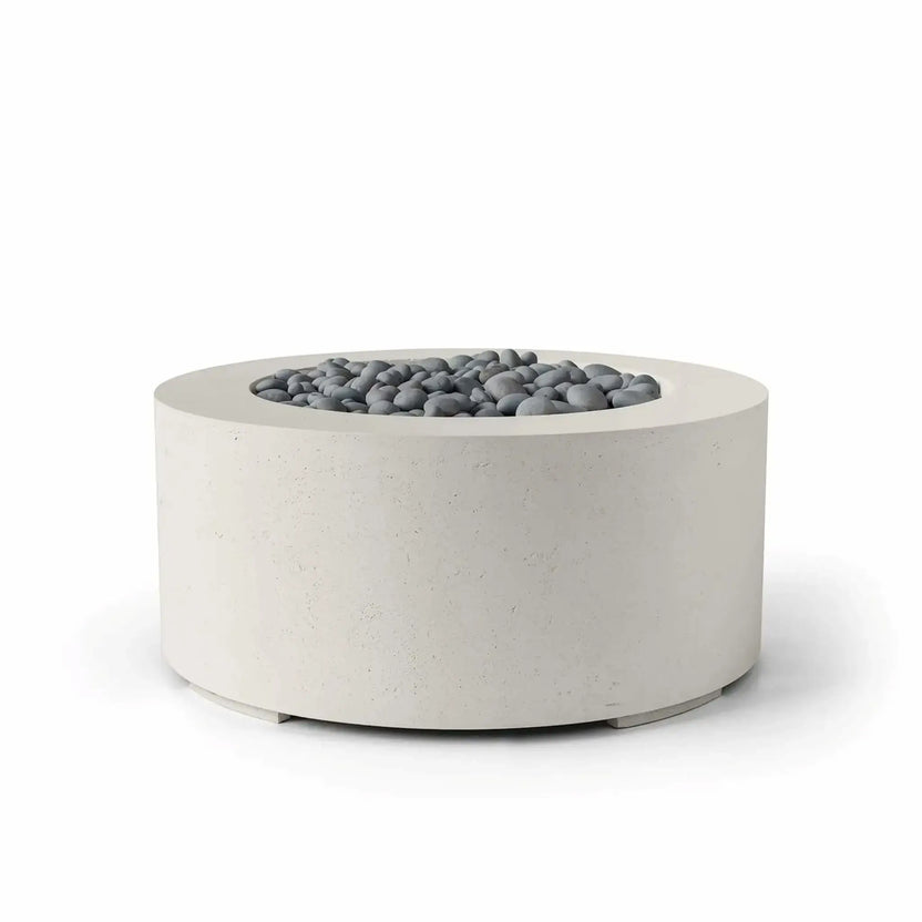 HPC Fire Hearth Products Controls Dekko GFRC Concrete Belmont Fire Pit in Limestone finish showcasing slate stone fire media. This contemporary round fire pit features durable GFRC concrete construction, a smooth recessed burner opening, and decorative gray slate stones. The neutral limestone finish and clean architectural form create a sophisticated outdoor centerpiece suited for modern patios, courtyards, hospitality spaces, and luxury outdoor living areas.