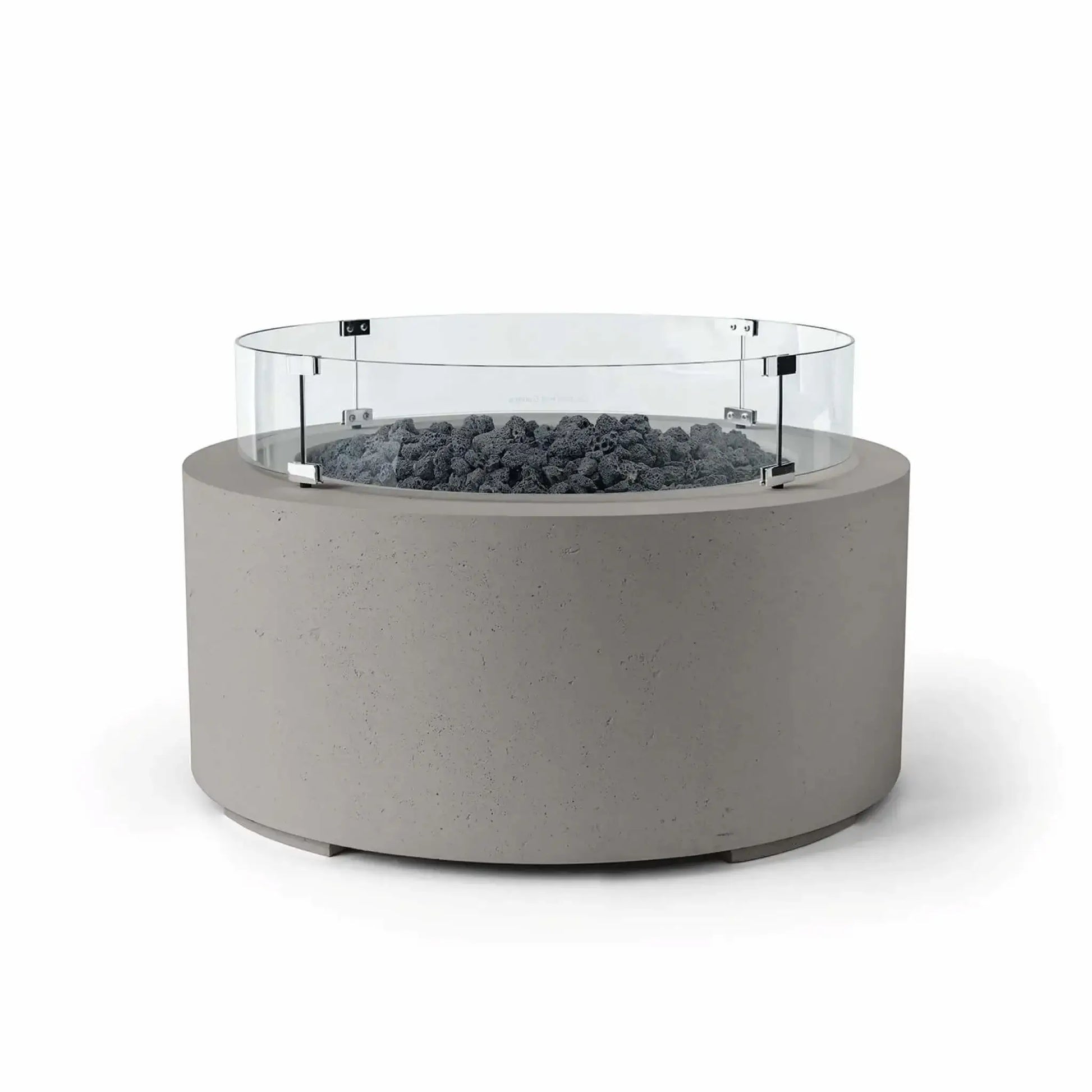 HPC Fire Hearth Products Controls Dekko GFRC Concrete Belmont Fire Pit in Sandstone finish featuring Lava Rock media and a Tempered Glass Wind Guard. The round fire pit showcases a textured sandstone-colored GFRC concrete exterior, dark volcanic lava rock fire media, and a transparent circular windscreen mounted with stainless steel brackets. The Belmont Fire Pit offers a sophisticated blend of natural textures and contemporary outdoor styling.
