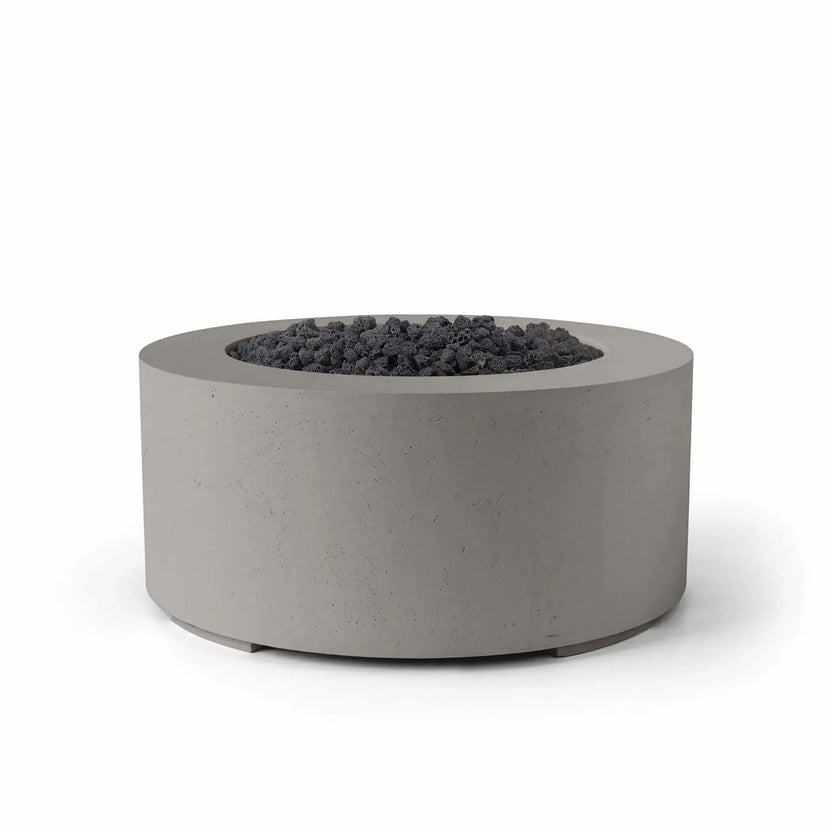 HPC Fire Hearth Products Controls Dekko GFRC Concrete Belmont Fire Pit in Sandstone finish featuring black lava rock media. The round outdoor fire pit showcases a textured GFRC concrete body, broad circular rim, and recessed fire area filled with rugged volcanic rock. The warm sandstone finish paired with dark lava rock creates a bold contemporary look, making the Belmont Fire Pit an attractive focal point for patios, outdoor lounges, and commercial landscapes.